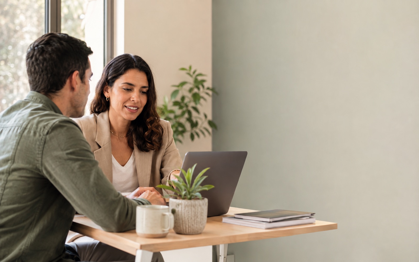Asesora comercial y colega revisan oportunidades de negocio en una notebook